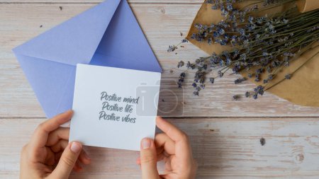 POSITIVE MIND LIFE VIBES text on supportive message paper note reminder from violet envelope. Flat lay composition dry lavender flowers. Concept of inner happiness, slowing-down digital detox personal