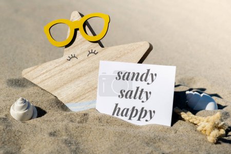 SANDY SALTY HAPPY text on paper greeting card on background of funny starfish in glasses summer vacation decor. Beach sun coast. Slowing-down, enjoying the moment, good moments, slow life Holiday