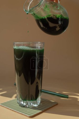 Bebida en polvo de algas Espirulina verde orgánica natural sobre fondo beige neutro. Clorella algas veganas superalimentos cócteles smoothie fuente suplemento y desintoxicación de beber. Ingrediente innovador