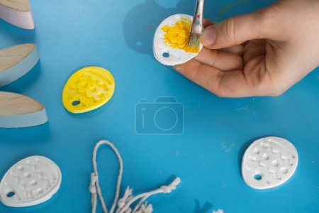 Master class of coloring Creator está utilizando arcilla seca al aire blanco para hacer decoración para las vacaciones de Pascua. Creación de actividad recreativa hobby que involucra los dedos. Artesanía de bricolaje Arte moderno 