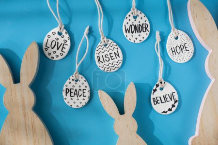 Group of wooden bunny ears and clay Easter eggs with words RISEN HOPE BELIEVE PEACE LOVE WONDER White air dry clay for making decor to EASTER holiday. Creating hobby recreation activity that involves