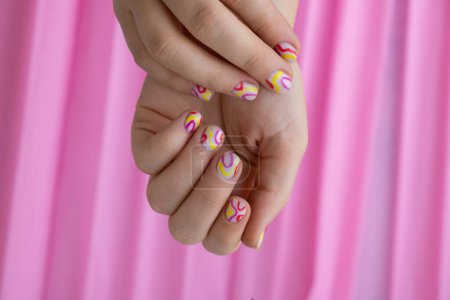 Pastel suavidad colorido manicura uñas sobre fondo rosa. Mujer mostrando su nueva manicura de verano en colores pastel paleta. Simplicidad decoración fresco primavera vibraciones color tierra tonos neutros diseño