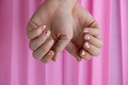 Stylish colorful summer female nails on pink background. Modern trendy stylish Beautiful manicure. Cute pastel nail minimalistic design concept of beauty treatment. Gel nails. Skin care. Beautician