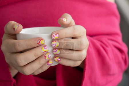 Foto de Elegantes uñas femeninas de verano de colores sosteniendo la taza blanca de café o té. Moderno de moda elegante Hermosa manicura. Lindo concepto de diseño minimalista de uñas pastel de tratamiento de belleza. Clavos de gel. Piel - Imagen libre de derechos