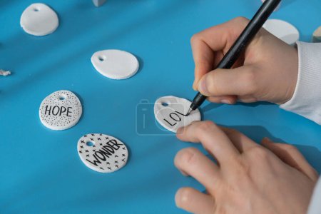 Master class writing word LOVE on EASTER egg Creator is using white air dry clay for making decor to EASTER holiday. Creating hobby recreation activity that involves fingers. DIY crafting Modern art 