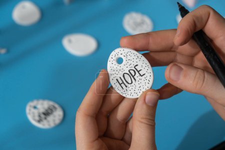 Workshop writing word HOPE on EASTER egg Creator is using white air dry clay for making decor to EASTER holiday. Creating hobby recreation activity that involves fingers. DIY crafting Modern art 