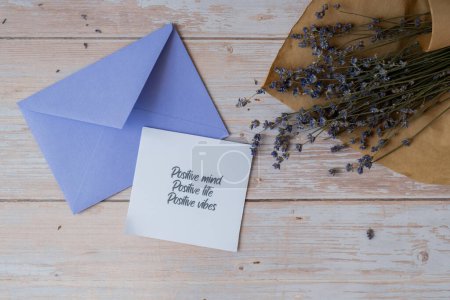 POSITIVE MIND LIFE VIBES text on supportive message paper note reminder from violet envelope. Flat lay composition dry lavender flowers. Concept of inner happiness, slowing-down digital detox personal
