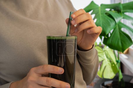 Mains féminines tenant des algues bleu-vert bio spiruline boisson de désintoxication dans les aliments en poudre de verre. Cocktail santé protéines smoothie de chlorelle. Vitamines et minéraux à l'alimentation. Prébiotique et antioxydant riche