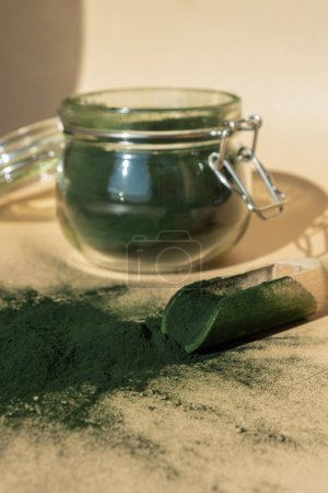 Organic blue-green algae spirulina powder food in glass jar with wooden spoon. Health benefits of spirulina chlorella. Vitamins and minerals to diet. Detox dietary supplement Seaweed superfood concept
