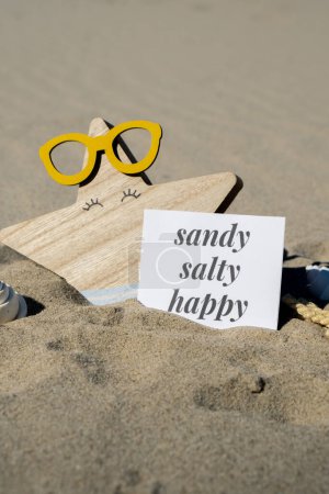 SANDY SALTY HAPPY text on paper greeting card on background of funny starfish in glasses summer vacation decor. Beach sun coast. Slowing-down, enjoying the moment, good moments, slow life Holiday