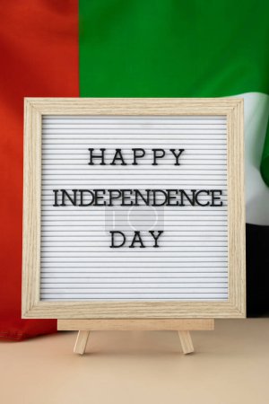 HAPPY INDEPENDENCE DAY text frame on United Arab Emirates waving flag made from silk material. Commemoration Day Muslim Public holiday celebration background. The National Flag of UAE. Patriotism