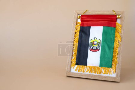 National symbol of UAE. United Arab Emirates small flag with Peregrine falcon on neutral beige background. Copy space for your text. Concept of National day Independence 