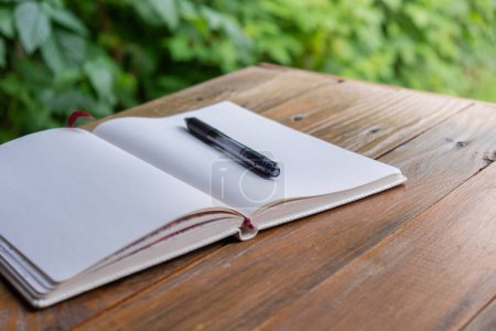 Ouvrir un bloc-notes en papier blanc vide sur une table en bois à l'extérieur. Concept d'écriture auteur dans une atmosphère détendue et confortable. Santé spirituelle détox numérique ralentir les pratiques 