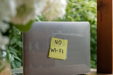 NO WI FI Text auf Papier Notiz am Laptop auf dem Hintergrund von Grün Garten hölzerne Nische im Freien. Konzept der Social-Media-Technologie Detox. Farmcore Natur Kern nachhaltiges langsames Leben