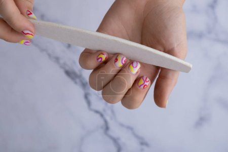 Maniküre-Werkzeuge Pastell Weichheit bunte manikürte Nägel. Frau zeigt ihre neue Sommer-Maniküre in Pastellfarben. Schlichtheit Dekor frischen Frühling Vibes erdfarbenen neutralen Tönen Design