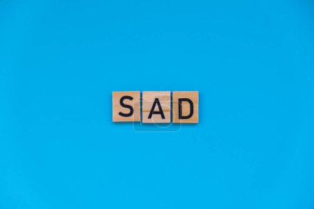 Saisonale affektive Störung - Text aus Holzblöcken auf blauem, hellem Hintergrund. Konzept der Depression Stimmungsstress und Angst. Trauriges Wohlbefinden 