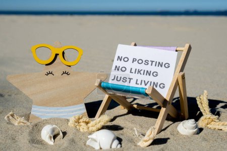 NO POSTING NO LIKING JUST LIVING text on paper greeting card on background of beach chair lounge starfish summer vacation decor. Concept of social media technology detox Sandy beach sun. Holiday postcard. Travel Business concept