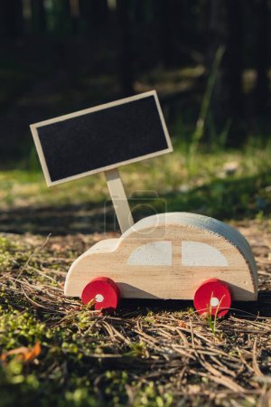 Empty blackboard with copy space Wooden toy car on greenery forest background. Eco-car concept World car free day electric vehicle environment automobile transportation electric vehicle. Hybrid