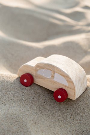 Wooden toy car on sandy beach background. Eco-friendly travel, reduce carbon footprints, environmental impact, Conscious Traveler, Environmentally Friendly, responsible traveler Eco-car concept World