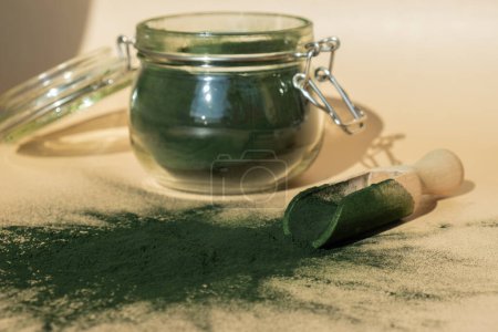 Organic blue-green algae spirulina powder food in glass jar with wooden spoon. Health benefits of spirulina chlorella. Vitamins and minerals to diet. Detox dietary supplement Seaweed superfood concept