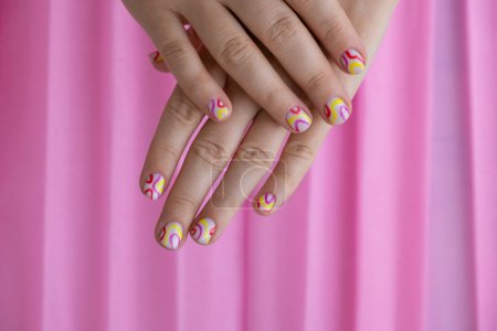 Pastel softness colorful manicured nails on pink background. Woman showing her new summer manicure in colors of pastel palette. Simplicity decor fresh spring vibes earth-colored neutral tones design