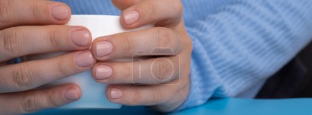 Stylish nude beige female nails on white cup. Modern trendy stylish Beautiful manicure. Cute pastel nail minimalistic design concept of beauty treatment. Gel nails. Skin care. Beautician