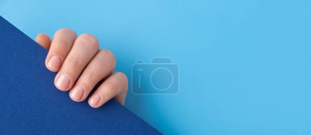 Foto de Pastel suavidad manicura uñas sobre fondo azul. Simular el espacio de copia de la plantilla Mujer mostrando su nueva manicura en colores de la paleta pastel. Simplicidad decoración fresca primavera vibraciones tierra-color neutro - Imagen libre de derechos