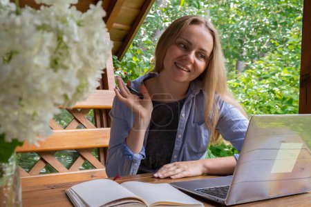 Mujer joven freelancer que trabaja en línea utilizando el ordenador portátil y disfrutar de la hermosa naturaleza al aire libre en el jardín. Educación en línea para reuniones. Worcation, trabajo de vacaciones, modelo de trabajo híbrido