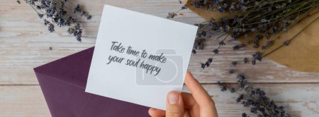TAKE TIME TO MAKE YOUR SOUL HAPPY text on supportive message paper note reminder from green envelope. Flat lay composition dry lavender flowers. Concept of inner happiness, slowing-down digital detox
