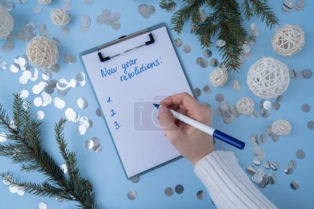 Photo for Female hands writing handwritten new year resolutions aims goals on paper notepad. Preparation for New Year. Concept of planning and setting goals for personal development - Royalty Free Image
