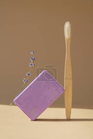 Bambus-Zahnbürste und Lavendelseife auf beigem Hintergrund mit Kopierraum für Ihren Text. Werbevorlage gefälscht. Hautpflege hausgemachte Naturkosmetik-Konzept. Trockene Lavendelblüte aus biologischem Anbau. Handgefertigt