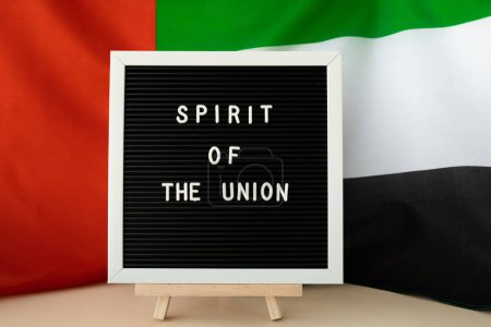 GEIST DES UNION-Textrahmens auf den Vereinigten Arabischen Emiraten schwenkt eine Fahne aus Seidenmaterial. Hintergrund der Feierlichkeiten zum Unabhängigkeitstag sind muslimische Feiertage. Die Nationalflagge der VAE