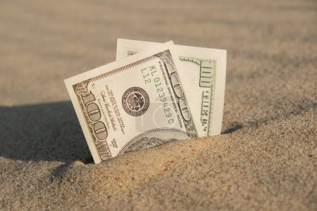 Money american hundred dollar bills in sandy beach. Concept finance saving money for holiday vacation. Costs in travel holidays. Shadows