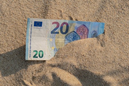 Dinero billetes de 20 euros en la playa de arena. Concepto de finanzas ahorrando dinero para vacaciones. Costes en vacaciones de viaje. Sombras