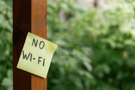 NO WI FI text on paper note on background of greenery garden wooden alcove outdoor. Concept of social media technology detox. Farmcore nature core sustainable slow life