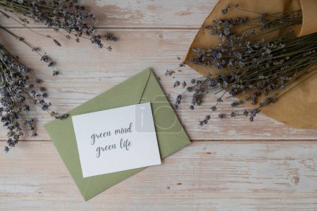 GREEN MIND GREEN LIFE text on supportive message paper note reminder from green envelope. Flat lay composition dry lavender flowers. Concept of eco-friendly lifestyle, environmental recyclable