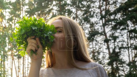 Young woman inhale fresh grown parsley from garden bed. Homegrown locally agriculture healthy country life concept. Farming 
