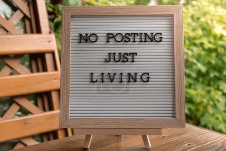 NO POSTING JUST LIVING text on letter board on background of greenery garden. Concept of social media technology detox. Farmcore nature core sustainable slow life