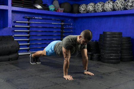 Photo for Latino athlete with sportswear in a gym doing high plank - Royalty Free Image