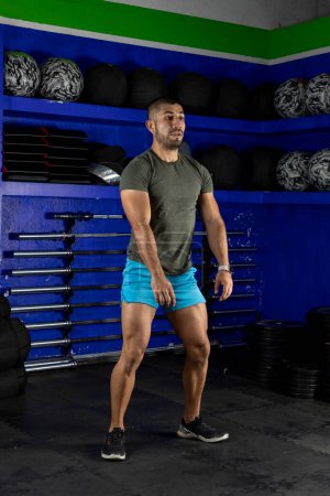 Photo for Vertical image of a latin man doing squats, wearing sportswear in a crossfit gym - Royalty Free Image