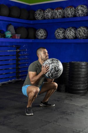 Photo for Latin man exercising in a gym, using a crossfit medicine ball - Royalty Free Image