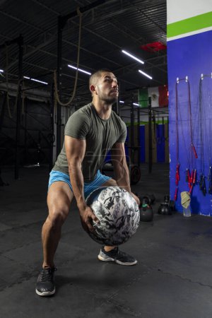 Photo for Man in sportswear exercising with a crossfit medicine ball, in a gym - Royalty Free Image