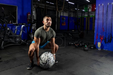 Photo for Man in sportswear exercising with a crossfit medicine ball, in a gym - Royalty Free Image