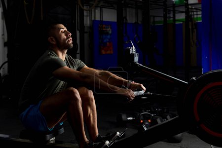Photo for Low light shot of an athlete rowing in a gym - Royalty Free Image