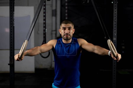 Photo for Portrait of an athlete standing leaning on gymnastic rings at a training site - Royalty Free Image
