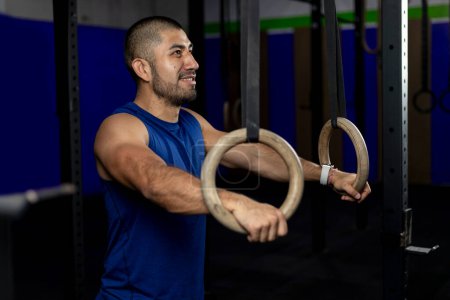 Photo for Portrait of an athlete standing leaning on gymnastic rings at a training site - Royalty Free Image