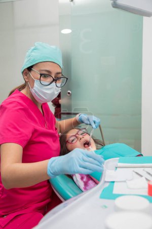 Photo for Dentist applying fluoride to a girls mouth in his office. - Royalty Free Image