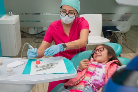 Photo for Girl smiling as her dentist prepares to give her teeth a cleaning - Royalty Free Image