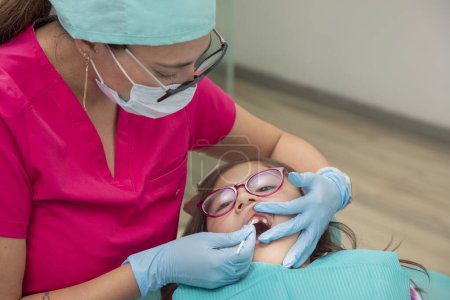 Photo for Dentist applying fluoride to a girl in his dental office - Royalty Free Image