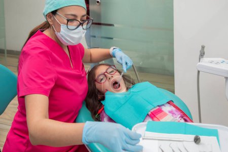Photo for Girl with her mouth open while her dentist gives her oral treatment - Royalty Free Image